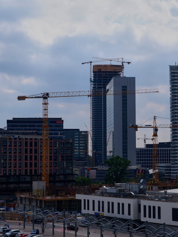 Cityscape of Bratislava showcasing skyscraper construction with towering cranes against a cloudy sky.